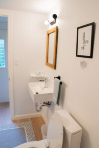 Modern bathroom vanity with sink, mirror, and bright lighting at Norma's Vacation Home in Stonington, Maine