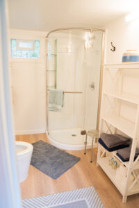 Clean bathroom featuring a walk-in corner shower, shelving, and fresh linens at Norma's Vacation Home in Stonington, Maine