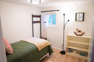 Cozy bedroom with twin bed, reading lamp, bookshelf, and window at Norma's Vacation Home in Stonington, Maine