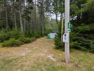 A white wooden post marker for Campsite G, ideal for tents and small RVs in Stonington, Maine. Island camping at its finest